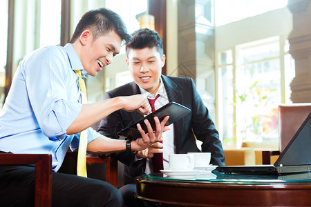 两位亚洲华裔商人或办公室人员在酒店大堂举行商务会议图片