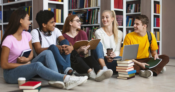 一群国际学生坐在书架旁边的地板上图片