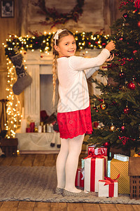 微笑的女孩装饰着圣诞树图片