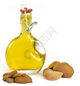 玻璃摇顶瓶中的杏仁油展示了采摘的杏仁图片