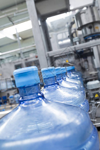 加工纯泉水并将纯泉水装瓶到使用加仑的机器人工厂线田间深度短图片