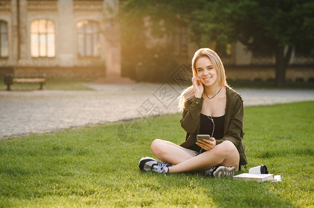 微笑的女学生坐在校园院子的草地上图片