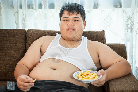 坐在沙发和看电视上吃快餐的懒惰图片