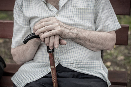 老人坐在户外的长木凳上老人手里拿着拐杖贫穷孤独图片