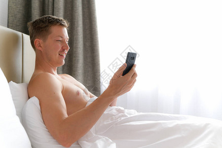 使用移动电话的男人在床铺图片
