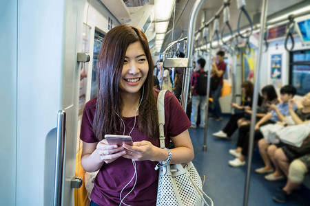 使用地铁智能移动电话在大城市旅行生活方式和交通概念的亚洲穿便衣女旅客图片