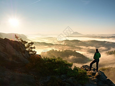 男子剪影停留在锋利的岩峰上满足徒步旅行者欣赏美景岩石峭壁的高个子观看下来风景生动而强背景图片