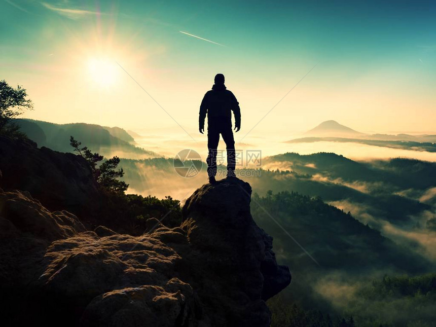 男子剪影停留在锋利的岩峰上满足徒步旅行者欣赏美景岩石峭壁的高个子观看下来风景生动而强图片