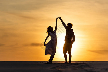 日落时男女在海滩对抗日背景图片