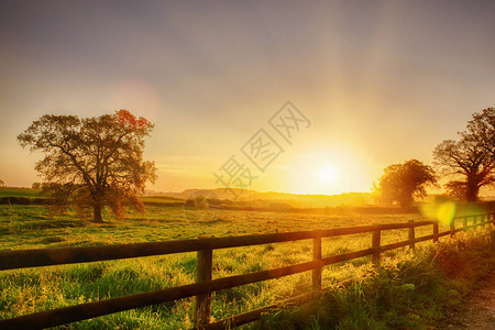 在英国诺福克草原的乡村地貌上光荣的日出两条栅图片
