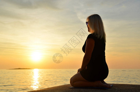 日落时坐在海边的瑜伽图片
