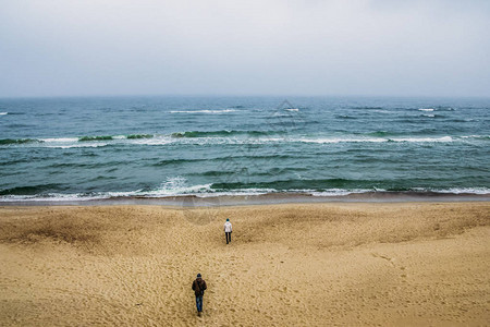 一对在岸上行走的情侣的后视线看着卷浪大海立陶宛图片