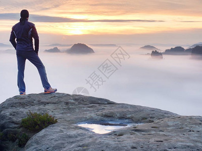 人独自站在岩石的顶端徒步旅行者在地平线上观看秋天的太阳美丽的时刻背景图片