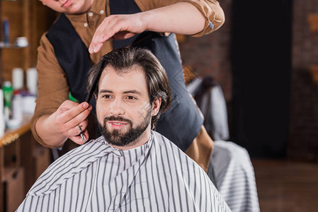 英俊的年轻男子在理发店专业理发图片