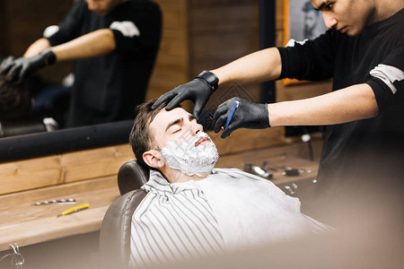 理发师使用锋利的剃刀为有胡子的人刮胡子图片