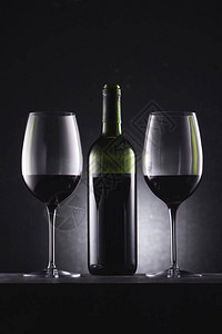 装满红色葡萄酒和红酒瓶的杯子图片
