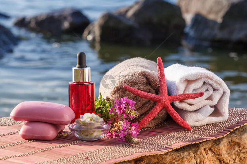 海盐碗香油瓶肥皂野花海星和石头上布有竹布的毛巾图片
