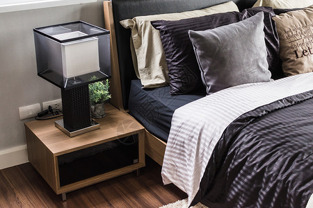 现代灰色卧室家里有木制床头柜和台灯图片