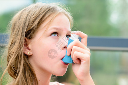 哮喘女孩使用哮喘吸入器保持健康浅景深图片