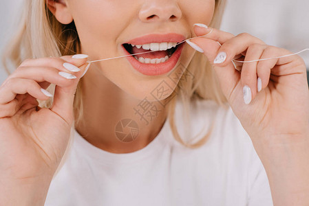 妇女用牙线刷牙的裁剪视图图片