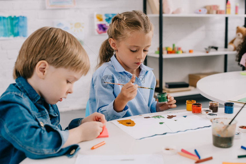 重点突出的学龄前儿童在课堂上用桌边的油漆和油图片
