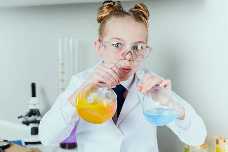 小科学家穿着实验室外套和防护眼镜在科学实验室用烧瓶中的图片