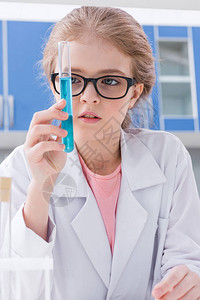 身着眼镜和白大衣在实验室内用试剂持有试管并装有试剂图片