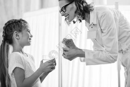 笑的医生给小女孩提供药品的侧面景图片