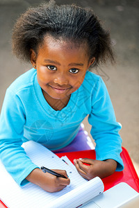 非洲小孩在办公桌前用笔记本写字的肖像图片