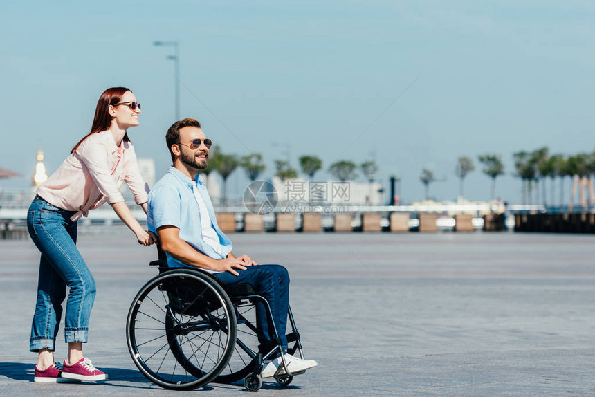 在街上推着英俊的男朋友坐在轮椅上的一面景象图片