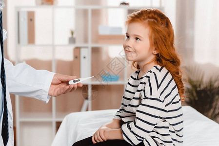 儿科医生给诊所中微笑的小女孩提供温度计的一图片