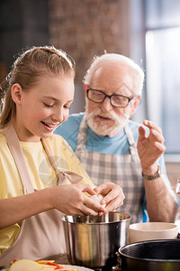戴眼镜的老人看着微笑的孙女在厨房图片