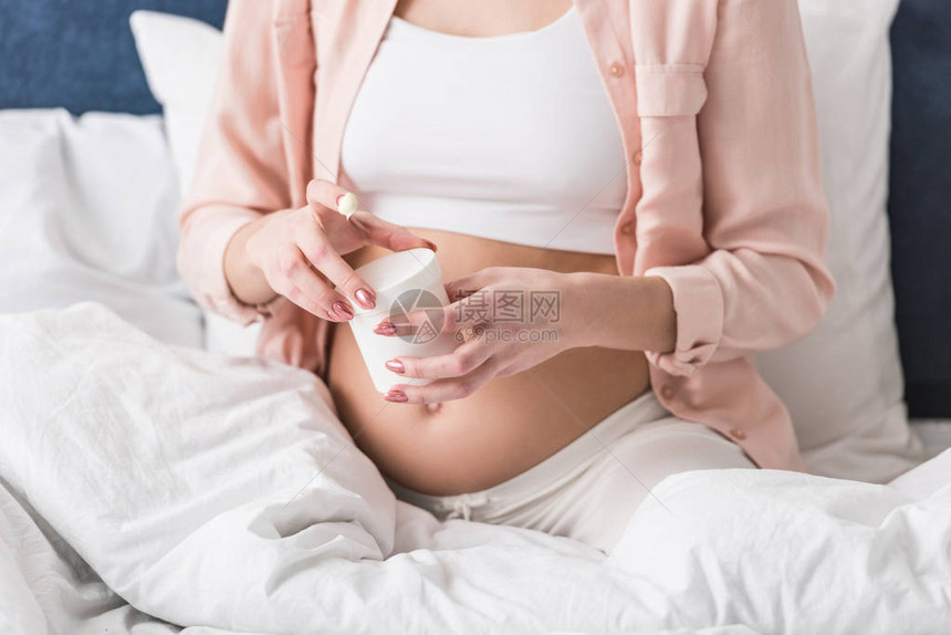 部分观察孕妇用奶油打开容图片