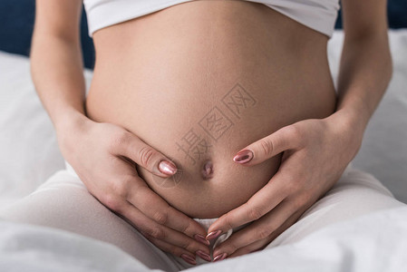 孕妇轻抚摸腹部的剪影图片