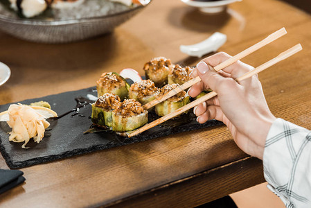 在餐厅里拿着筷子拿着寿司的女人的剪影图片