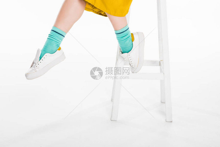穿着运动鞋坐在沙凳上孤立在白边的脚凳图片