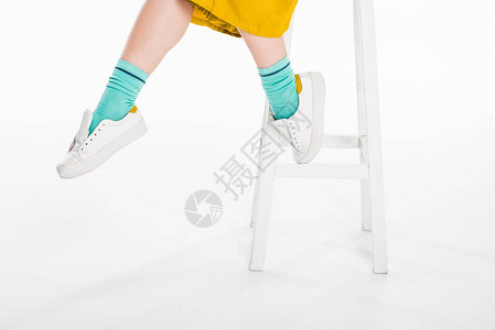 穿着运动鞋坐在沙凳上孤立在白边的脚凳图片