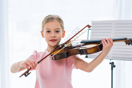 穿粉红裙子在家里拉小提琴的小提琴的图片
