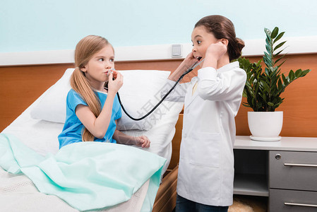 在医院里扮演医生和病人的可爱小女孩图片