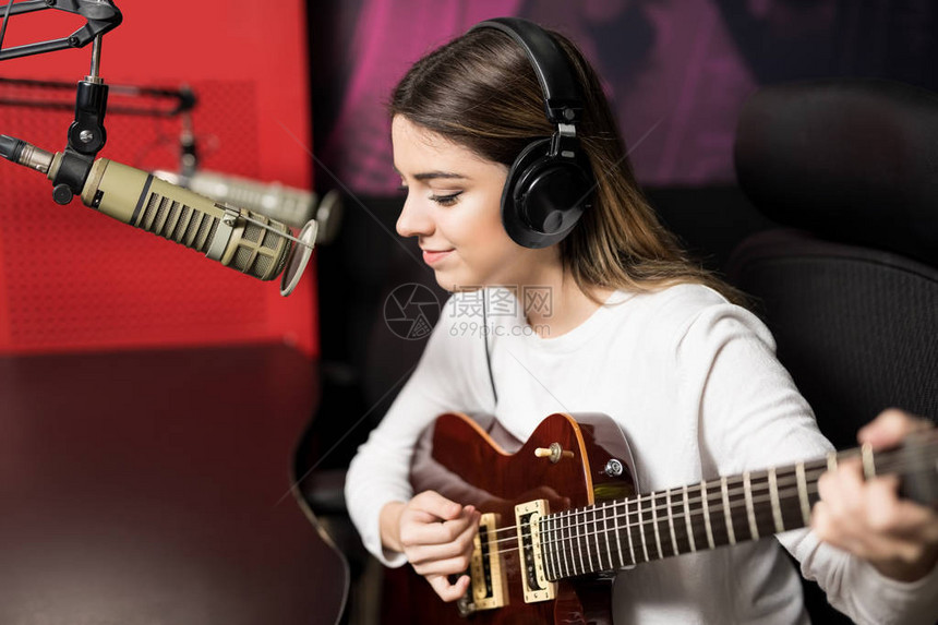 年轻女歌手在电台播放吉他和麦克风中唱歌图片