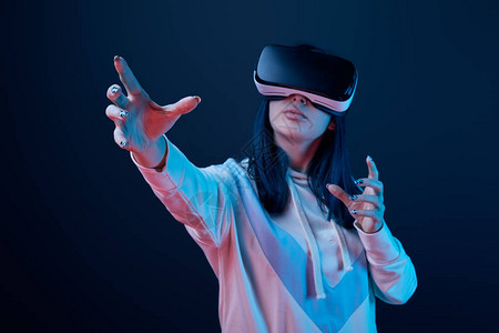 穿着虚拟现实头盔和穿蓝衣游览的年轻女有选择地聚图片