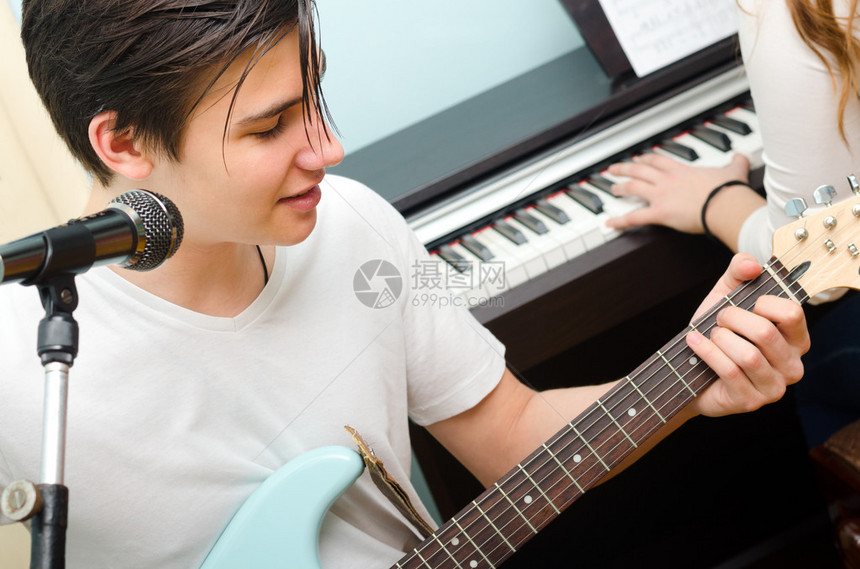 少年男孩玩电吉他和唱歌而女孩图片