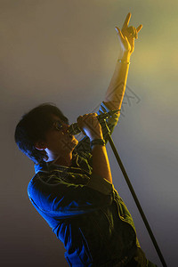 一个男人在聚光灯下唱着麦克风图片