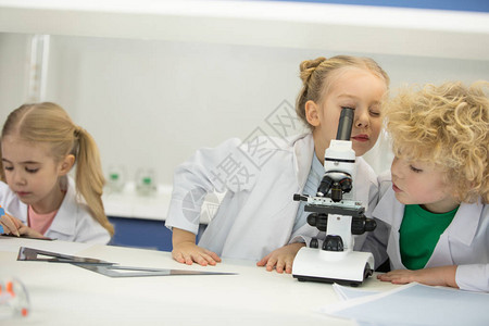 小孩子在科学课上用显微镜看背景图片