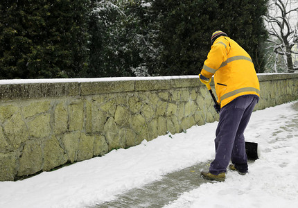 下雪后垃圾人从行道上铲雪图片