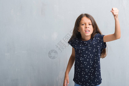 年轻的西班牙裔孩子在垃圾灰色的墙上愤怒和疯狂地举起拳头沮丧和愤怒图片
