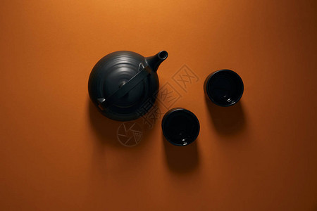 黑色陶瓷茶壶顶部的黑陶瓷茶壶和棕色背图片
