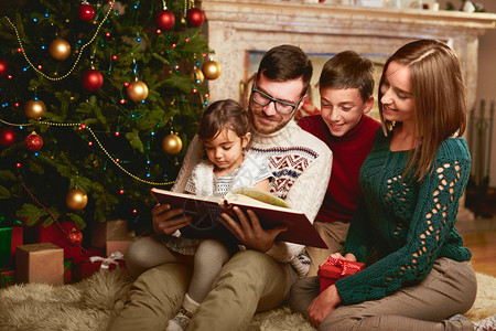 快乐的一家四口在圣诞节晚上一起读书图片