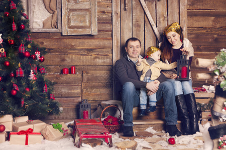 时尚的家庭在圣诞树上的房间里庆祝圣诞节穿着时髦针织毛图片