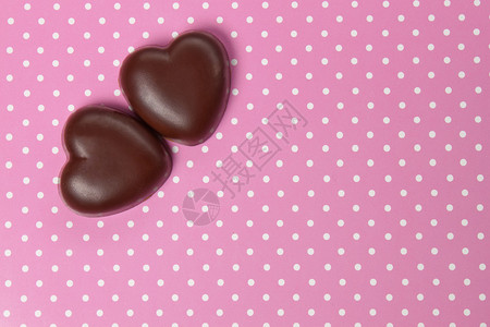 两颗巧克力糖果心放在背景上与波背景图片